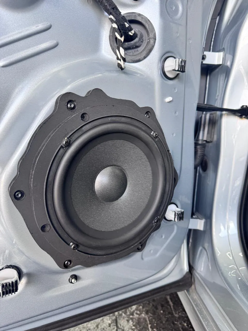 Alto-falante com adaptador instalado na porta de um carro prata