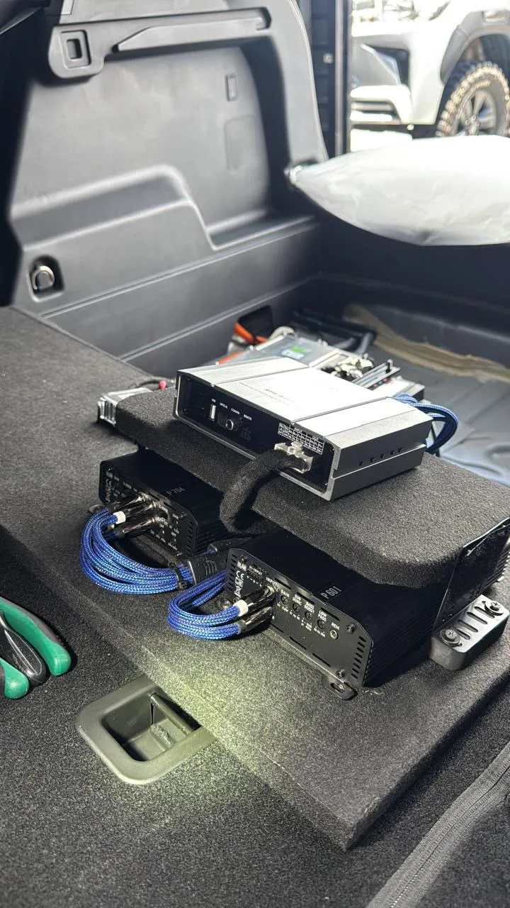Processador e amplificadores com cabos azuis trançados montados no porta-malas